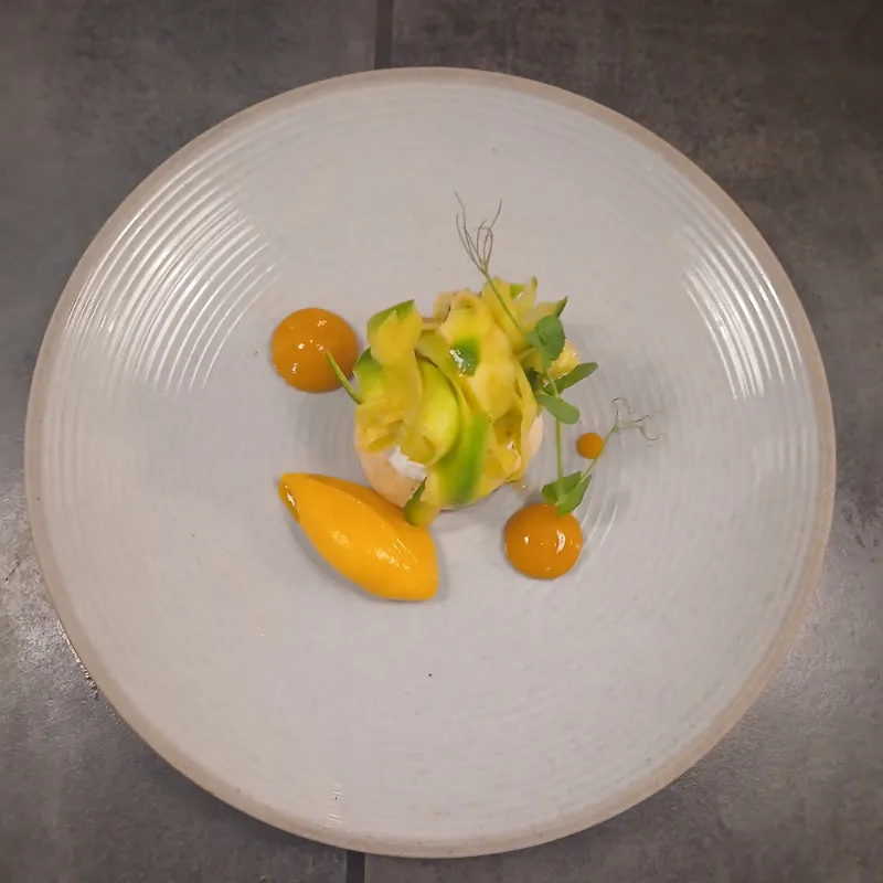 Une assiette dressée en cuisine : légumes en copeaux, sorbet et pointes de sauce