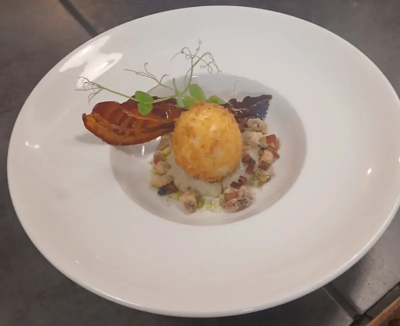 Une assiette creuse : œuf pané doré, lard croustillant et pousses